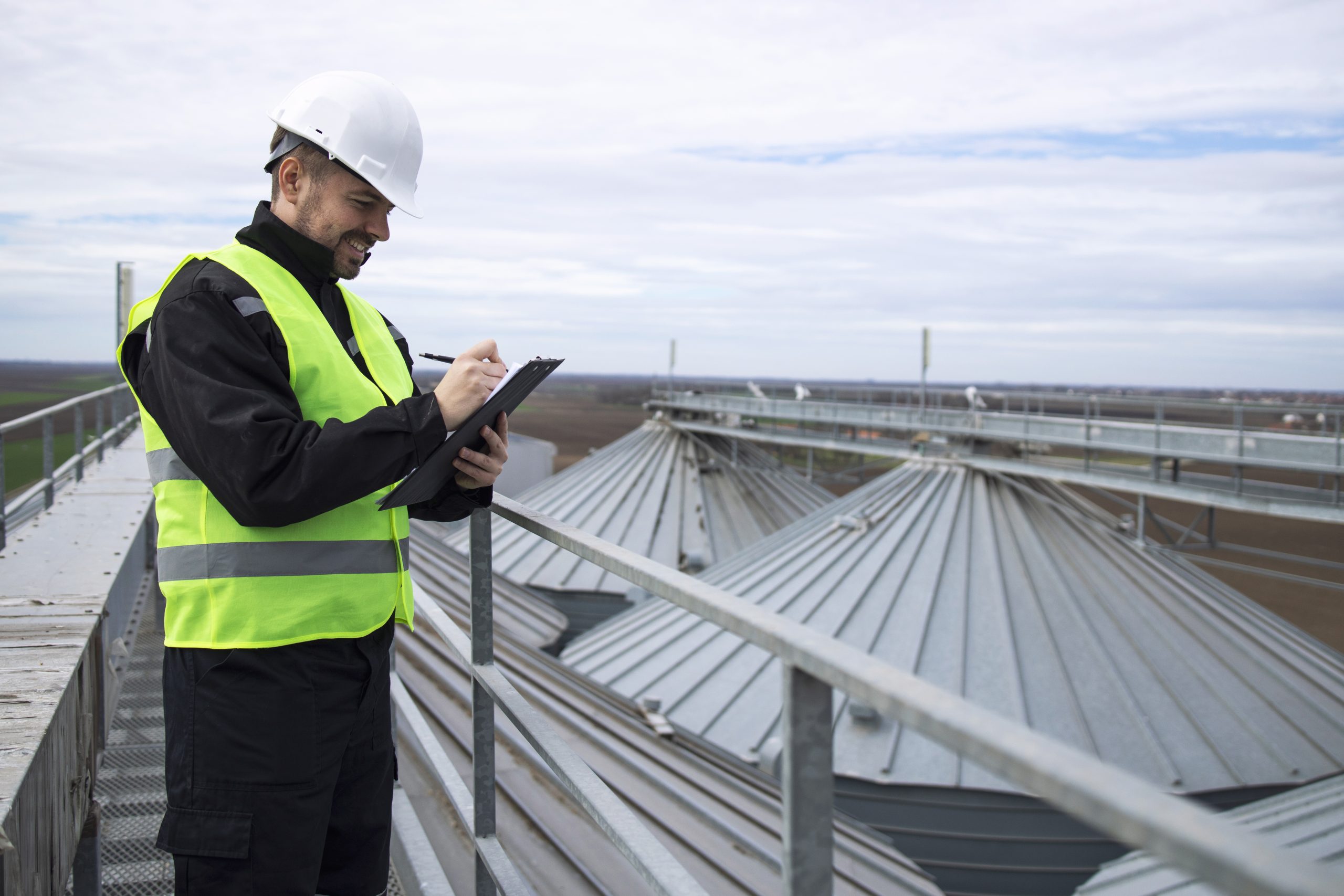 portrait construction worker standing rooftops high silos storage tanks working tablet computer scaled
